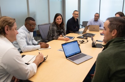 Men and women sitting around conference room table talking